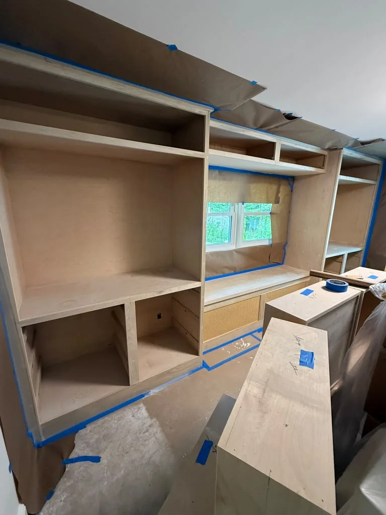 Custom built-in shelving units and bench with cane details, ready for finishing work. by ALP Home Services in Somerville, MA