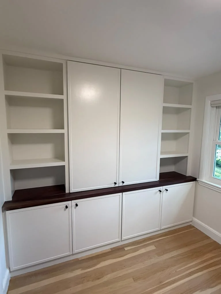 Custom built-in white cabinets with dark wood countertops and light hardwood flooring. by ALP Home Services in Somerville, MA