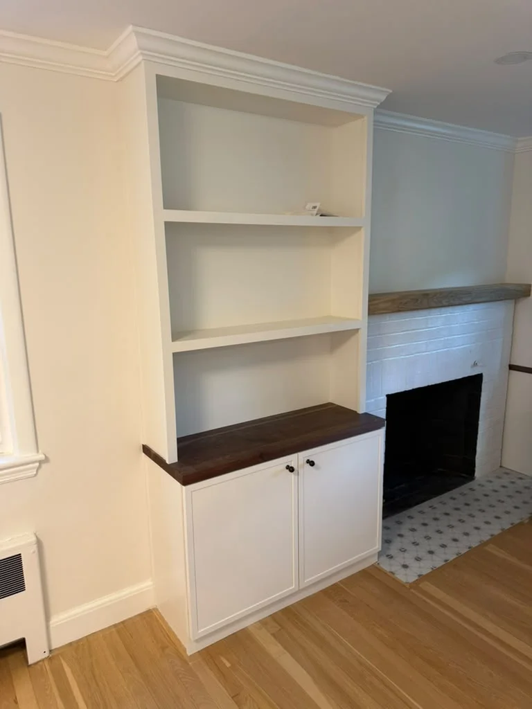 Custom Built-in Bookcase and Cabinet Custom white built-in bookcase and cabinet with dark wood top next to fireplace. by ALP Home Services in Everett, MA