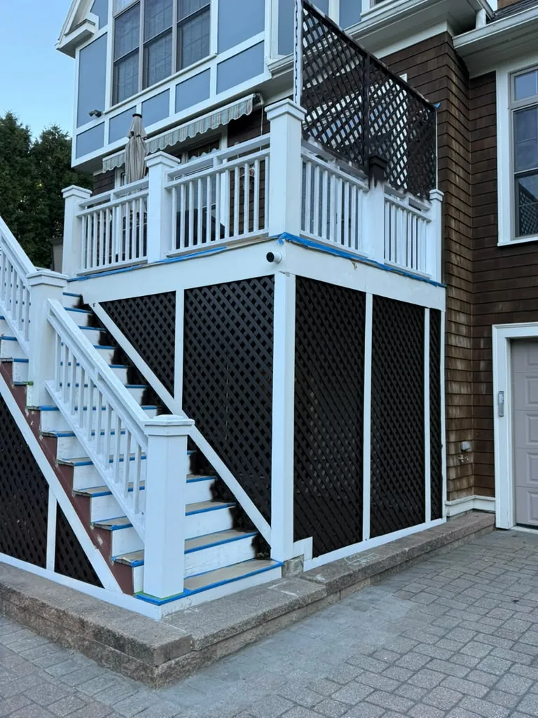 Deck painting in progress: railings primed white and taped, lattice skirting already in dark brown