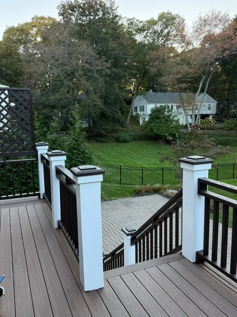 After: white posts with dark brown caps and a dark brown stair railing at the top of the deck stairs in Newton, MA