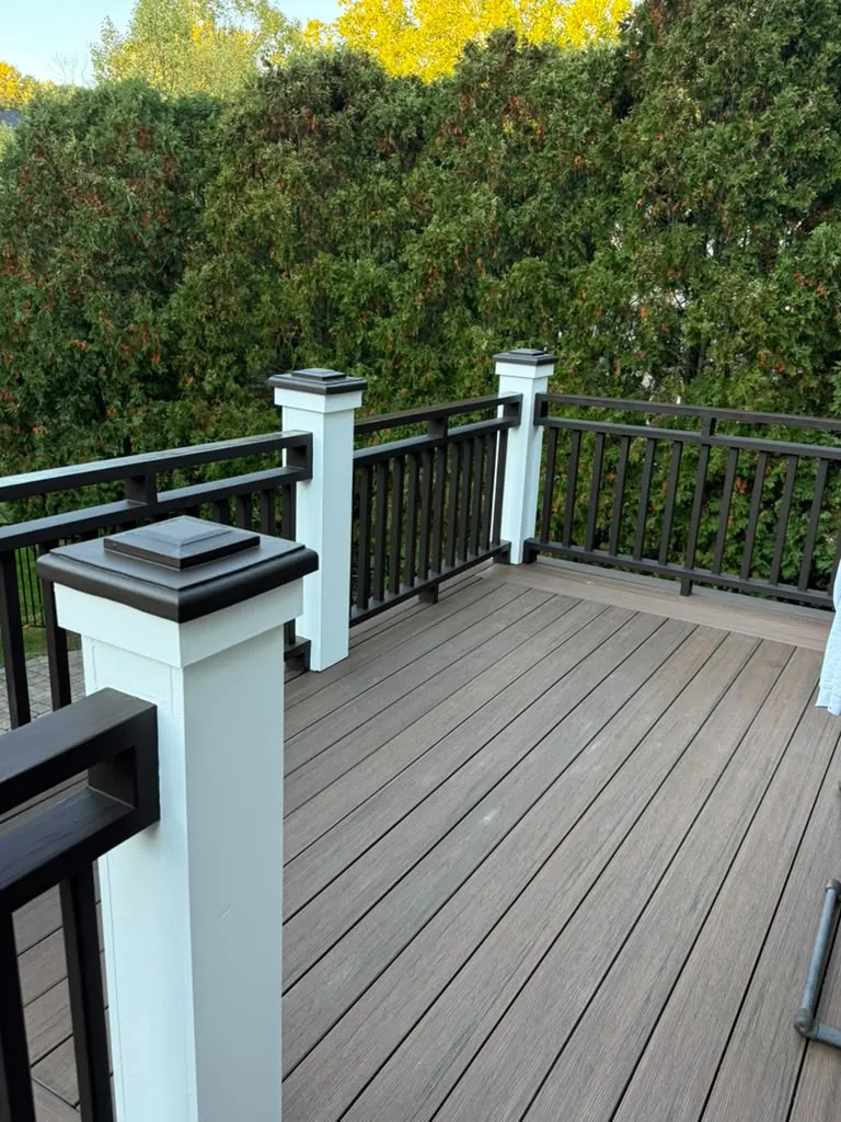 Finished deck corner with white posts, dark brown post caps and dark brown railings in Newton, MA