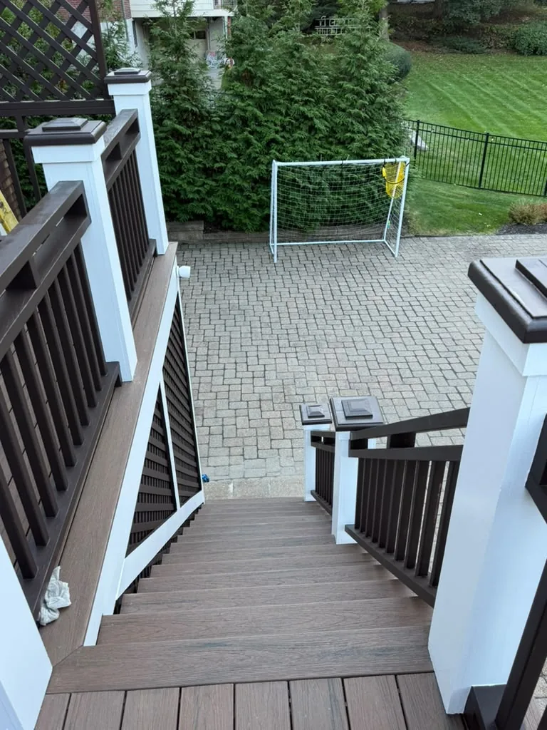 Finished deck stairs with dark brown balusters and handrail and white posts, painted by ALP Home Services