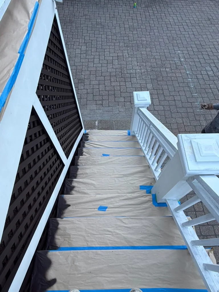 Deck stair painting prep: treads covered with paper, edges taped and railings primed white
