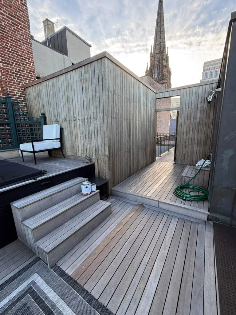 Before: gray weathered mahogany privacy screen and steps next to a rooftop hot tub in Back Bay, Boston