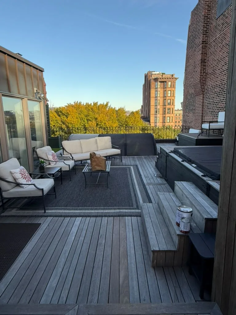 Before: weathered gray decking and steps by the lounge area of a rooftop terrace in Back Bay, Boston