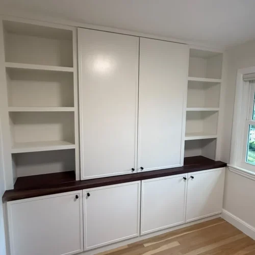 Custom built-in white cabinets with dark wood countertops and light hardwood flooring. by ALP Home Services in Somerville, MA
